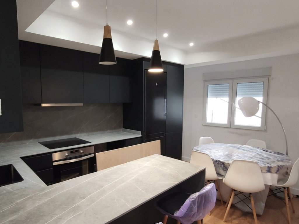 Cocina moderna negra conectada con comedor y zona de estar