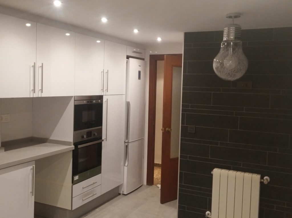 Cocina reformada con muebles blancos y electrodomésticos integrados en Valencia