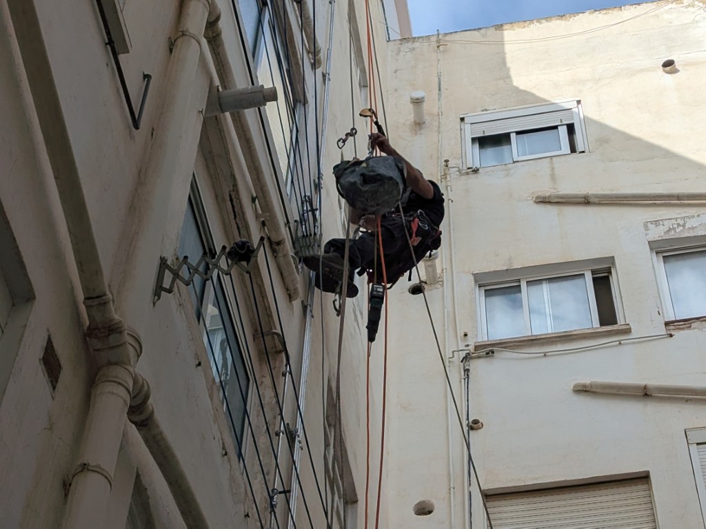 Trabajador realizando trabajos verticales en fachada de edificio