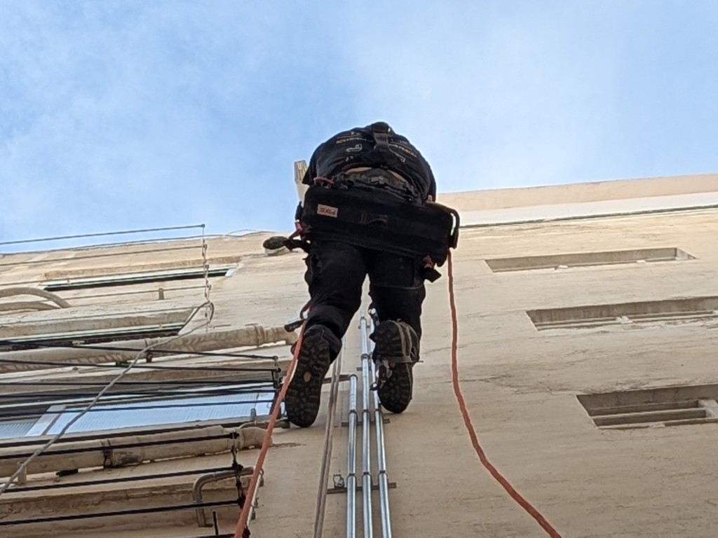 Trabajador realizando trabajos de reparación en patio interior mediante acceso por cuerda
