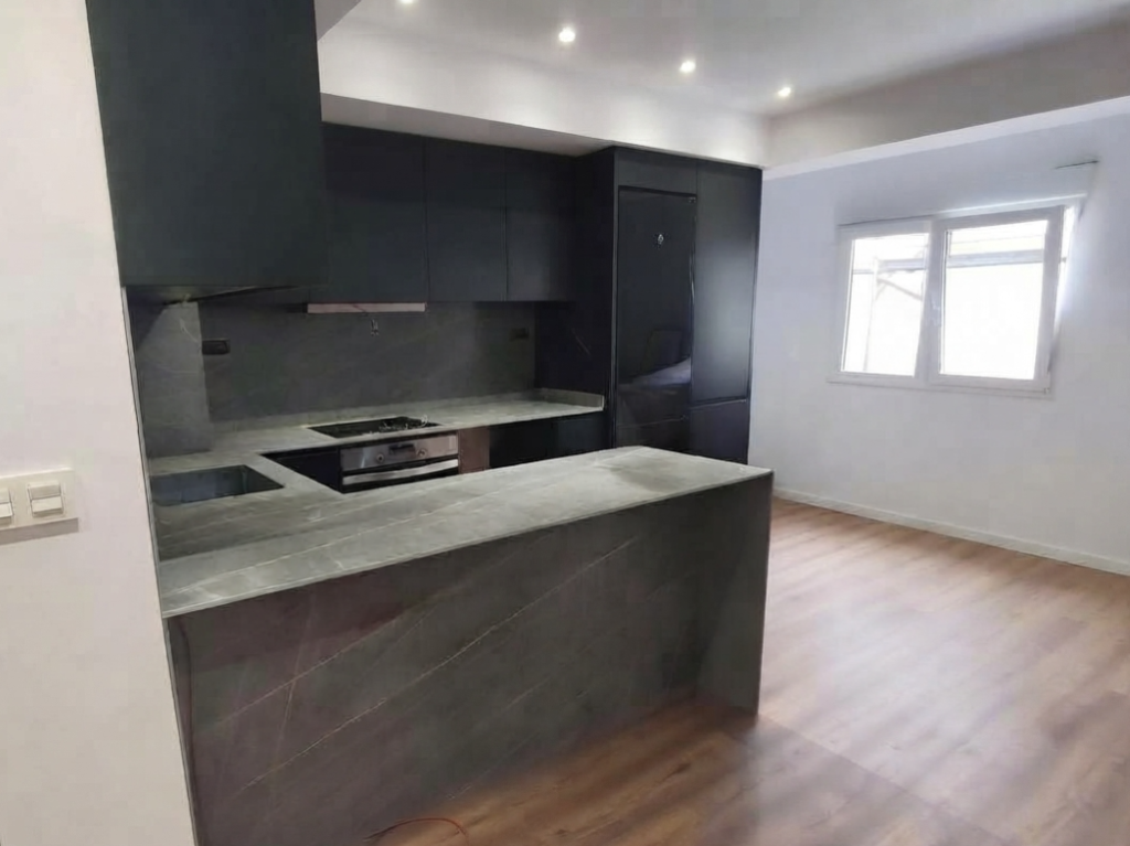 Encimera de cocina gris con fregadero, placa de inducción y muebles negros