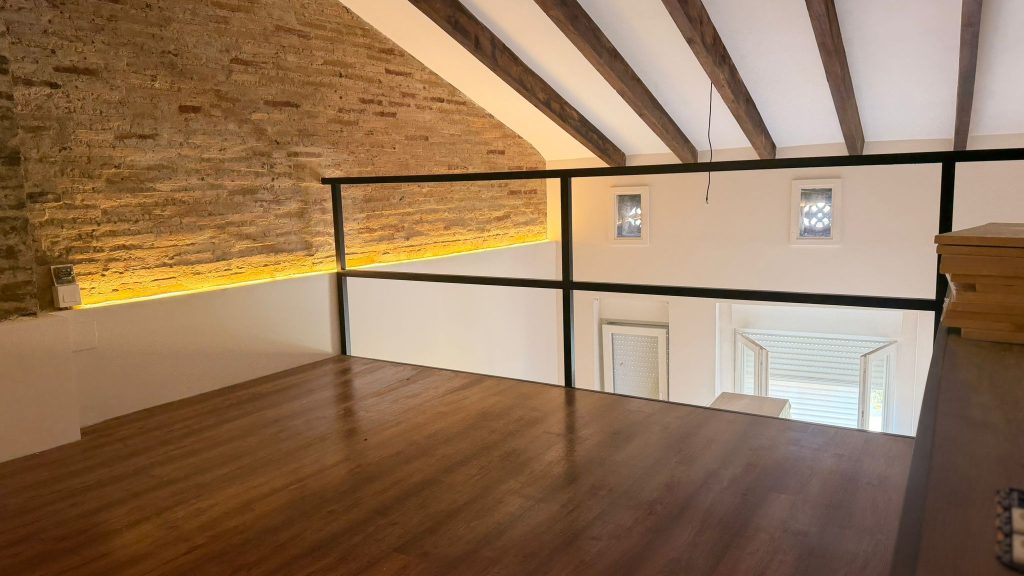 Altillo de madera con estructura metálica y escalera en una vivienda de Valencia