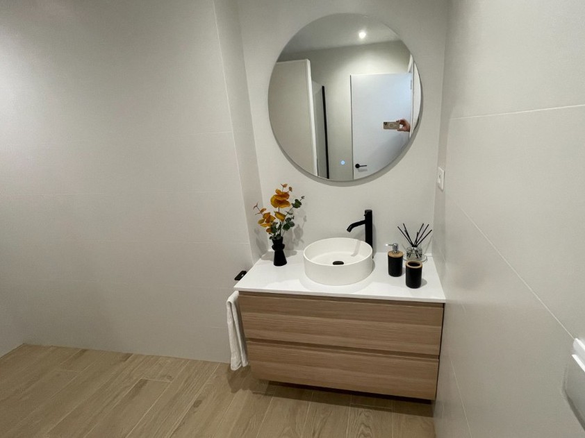 Baño reformado en Picanya con lavabo sobre encimera y mueble de madera