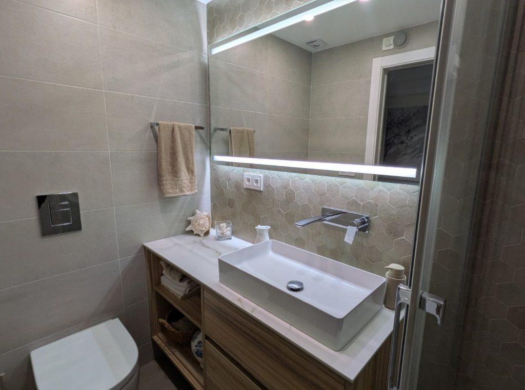 Mueble de lavabo y espejo retroiluminado en baño reformado en Valencia