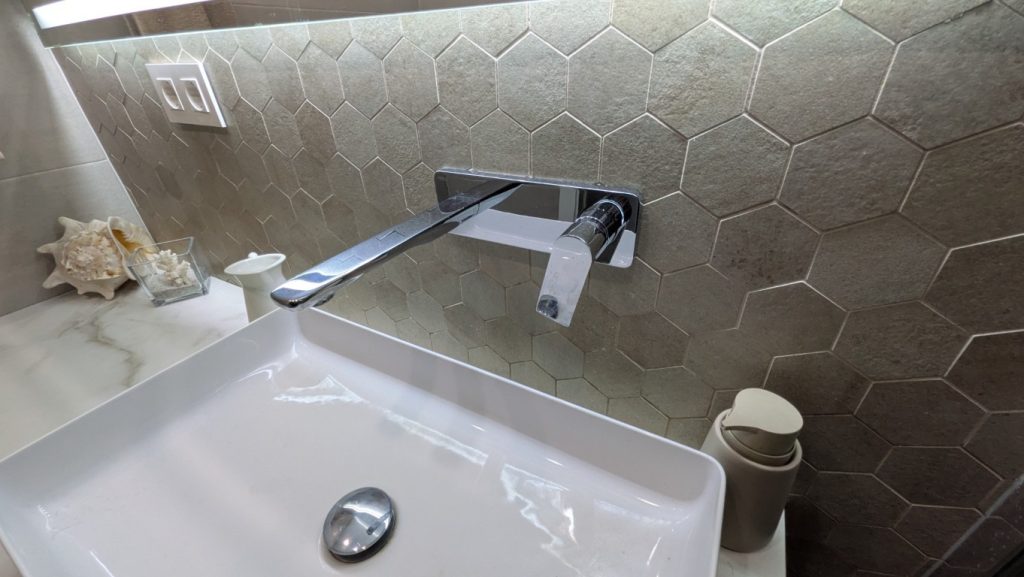 Revestimiento hexagonal y grifería mural en baño reformado de Valencia