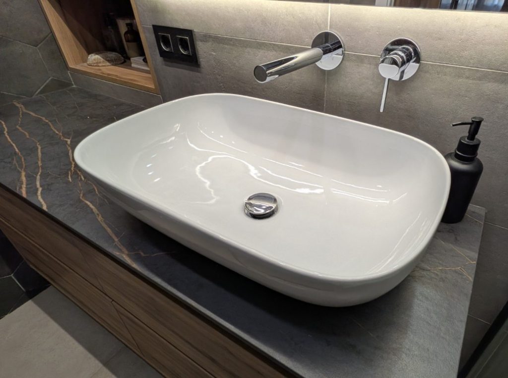 Lavabo blanco sobre encimera en baño reformado en Valencia