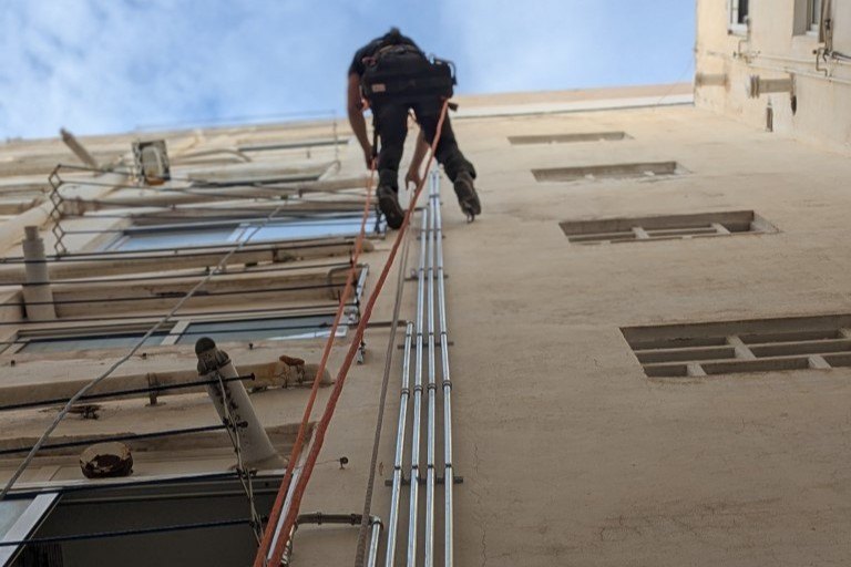 Operario realizando trabajos verticales en la fachada de un edificio